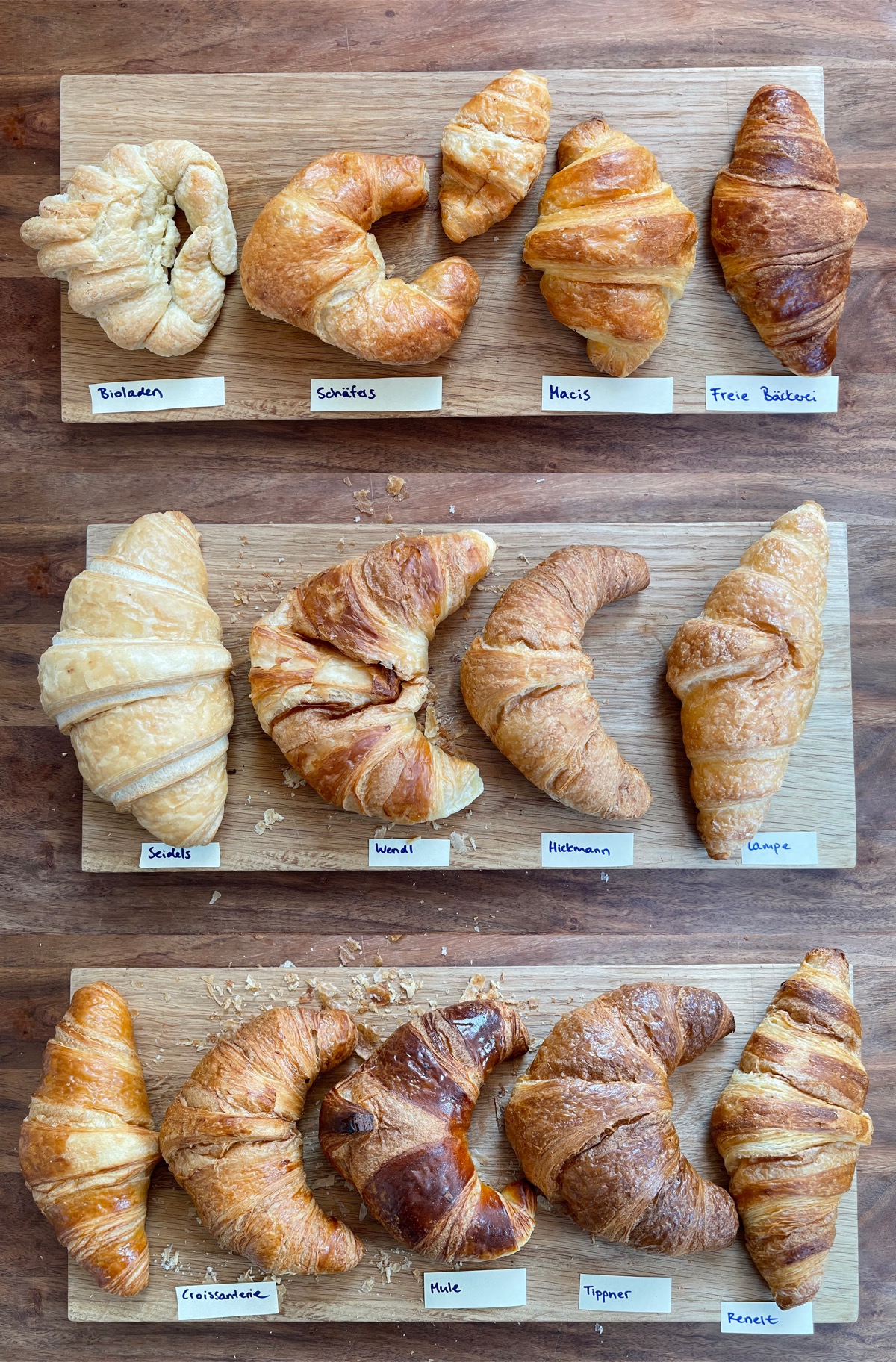 All 14 croissants laid out on cutting boards, labeled by bakery