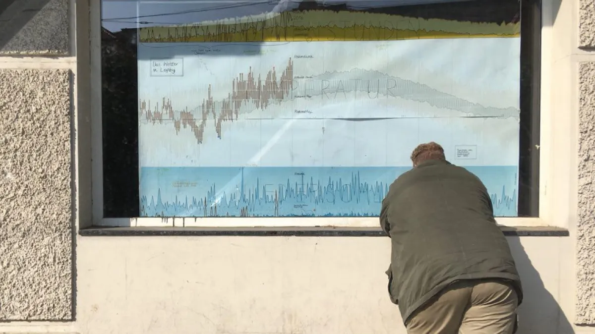 A passerby looks at the weather poster in a storefront window